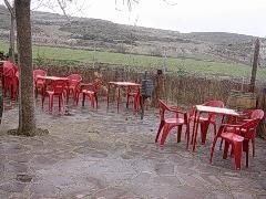 Terraza con mesas y sillas rojas junto al campo